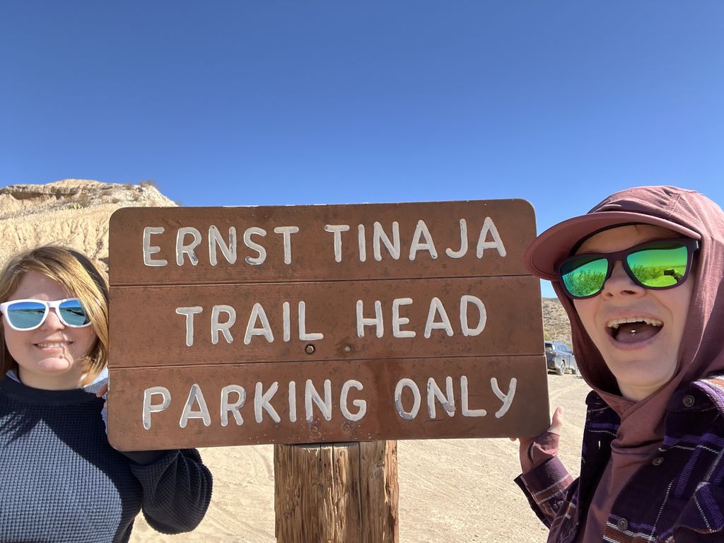 A dirt trail leading into a canyon with a rocky outcrop in the background.